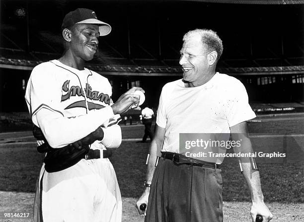 Satchel Paige shows Bill Veeck, owner of the Cleveland Indians, his new fastball grip before a night game at Municipal Stadium in Cleveland in 1949.