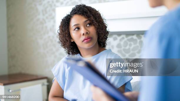 young patient looking at doctor in hospital ward - patient gown stock pictures, royalty-free photos & images