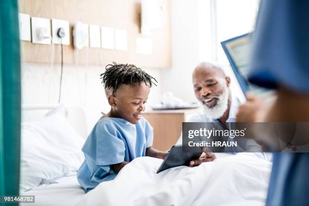 man met tablet pc aan ziek kleinzoon in ziekenhuis - hospital visit stockfoto's en -beelden