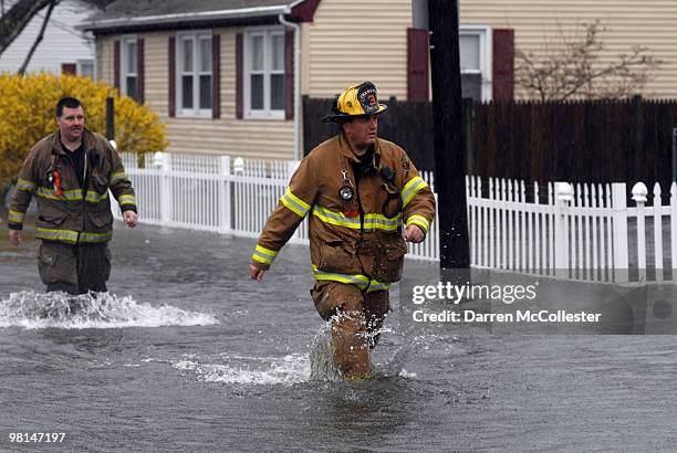 Firefighters wade in knee deep water due to flooding from the Pawtuxet River on Moore and Perkins Street March 30, 2010 in attempts to help local...