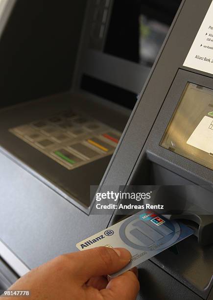 In this photo illustration a customer uses an ATM at an Allianz bank on March 30, 2010 in Berlin, Germany. Allianz focused on their core market...