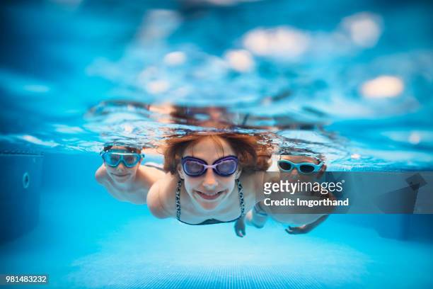 three happy kids swimming underwater in pool - family pool stock pictures, royalty-free photos & images