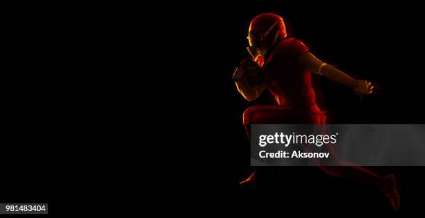 american football player with ball on a dark red background - phosphorescence stock pictures, royalty-free photos & images