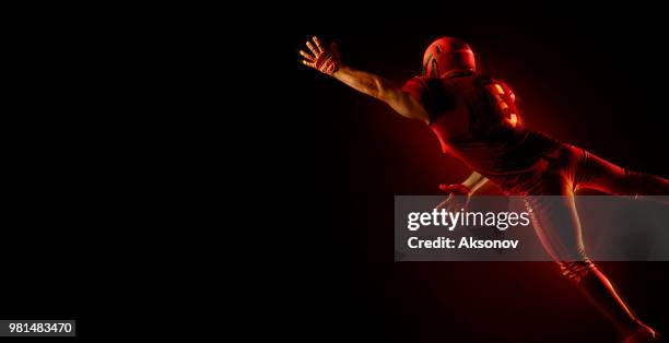 american football-spieler auf einem dunkelroten hintergrund - phosphorescence stock-fotos und bilder