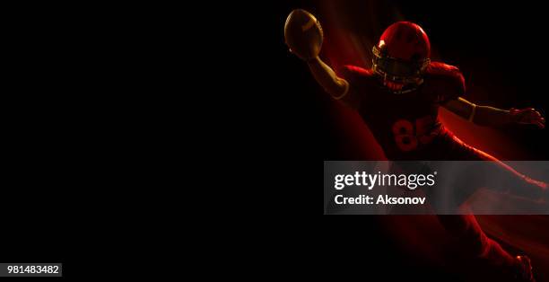 american football player with ball on a dark red background - phosphorescence stock pictures, royalty-free photos & images