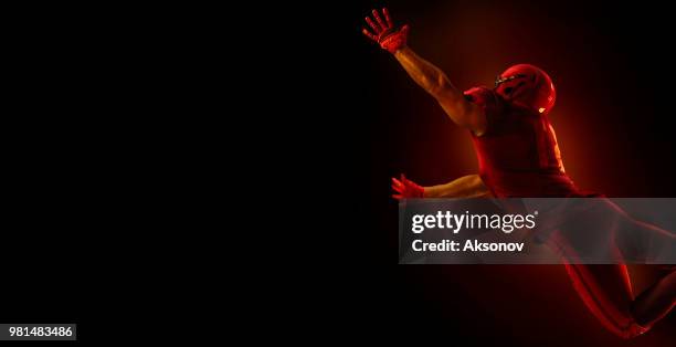 american football-spieler auf einem dunkelroten hintergrund - phosphorescence stock-fotos und bilder