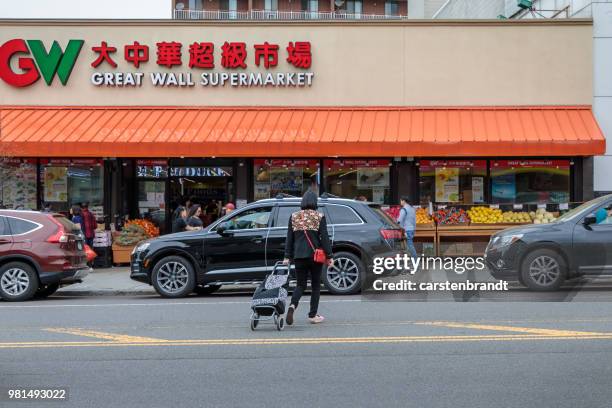 woman crossing main street in flushing - main street sign stock pictures, royalty-free photos & images