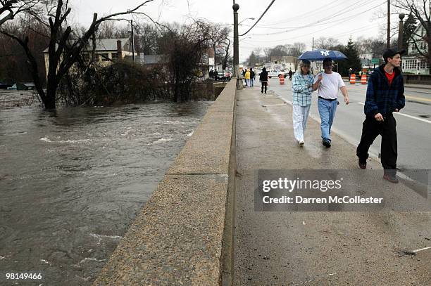 People walk over a bridge that spans the swollen Pawtuxett River March 30, 2010 on the Warick/Cranston line in Rhode Island. The second major rain...