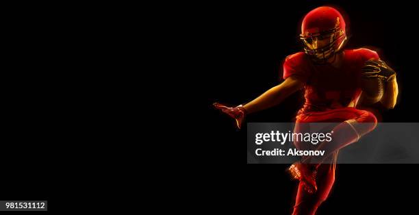 us-amerikanischer american-football-spieler mit ball auf einem dunkelroten hintergrund - phosphorescence stock-fotos und bilder