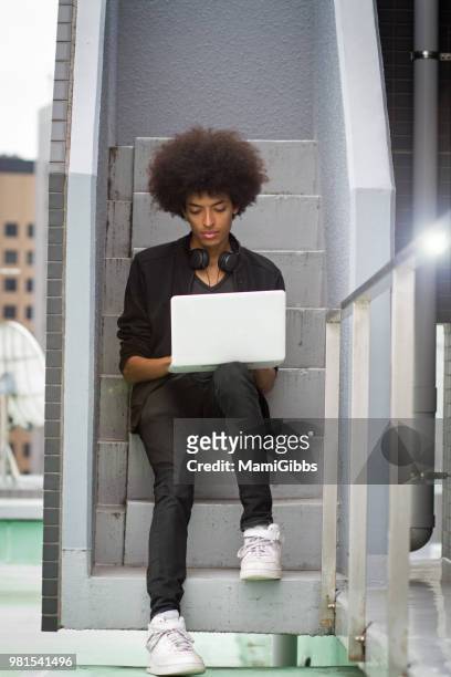 young man is working on a computer on the rooftop - mamigibbs stockfoto's en -beelden