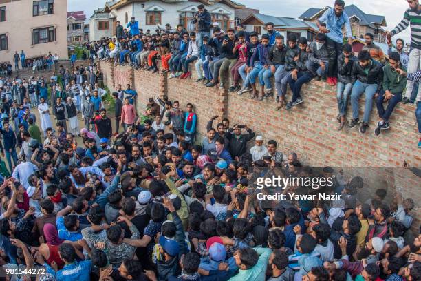 Kashmir Muslim on wall look towards the body being carried of Dawood Salafi, a rebel commander killed in a gun battle with Indian government forces...