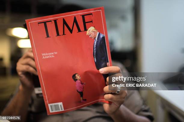 An AFP journalists reads a copy of Time Magazine with a front cover using a combination of pictures showing a crying child taken at the US Border...