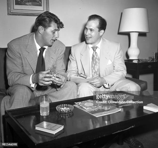 Entertainer Robert Mitchum poses for a portrait with bandleader Joe Reisman at the Sherry-Netherland Hotel on August 30, 1951 in New York.