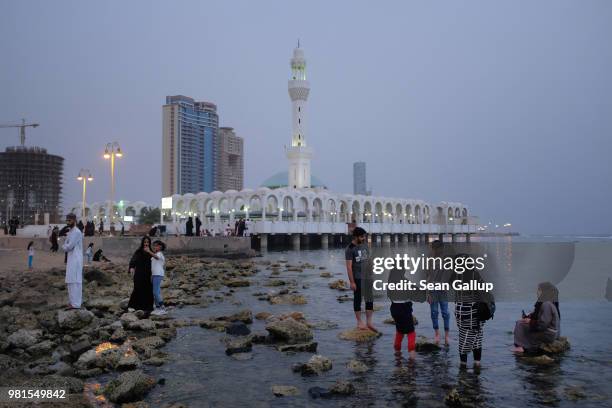 Teenagers step into the Red Sea on a Friday evening along the Corniche waterfront as the Al Rahma mosque stands behind on June 22, 2018 in Jeddah,...