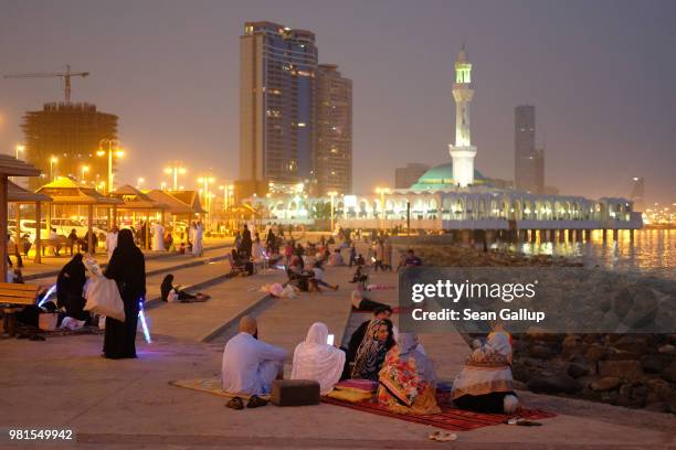 People relax on a Friday evening along the Corniche waterfront as the Al Rahma mosque stands behind on June 22, 2018 in Jeddah, Saudi Arabia. The...