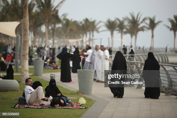 People, many of them wearing traditional Saudi garments, walk along the Corniche waterfront on June 22, 2018 in Jeddah, Saudi Arabia. The Saudi...