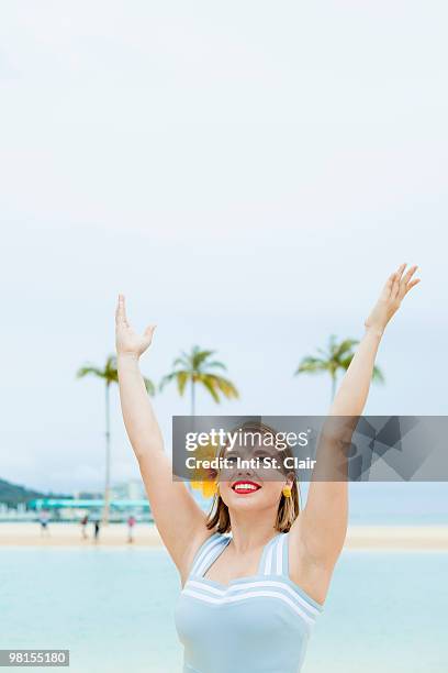 woman in 50s style sailor suit at beach, arms up - sailor arm stockfoto's en -beelden