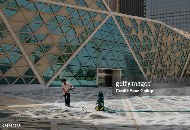 An immigrant worker cleans a plaza from sand with a hose at the newly-built King Abdullah Financial District on June 20, 2018 in Riyadh, Saudi...