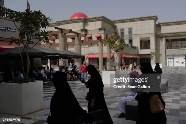 Women wearing the traditional Saudi niqab and black abaya walk across the central courtyard of Rubeen Plaza, a shopping center popular with young...