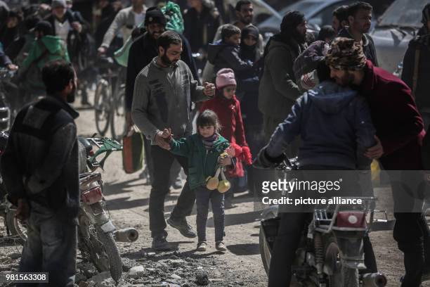 Syrian man holds the hand of a child while being evacuated from Zamlka in Syria's eastern Al-Ghouta province outside Damascus, Syria, 25 March 2018....