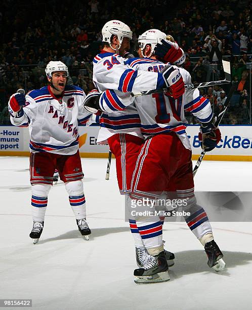 Marian Gaborik of the New York Rangers is mobbed by teammates Chris Drury and Aaron Voros after Gaborik scored a second-period goal in the game...