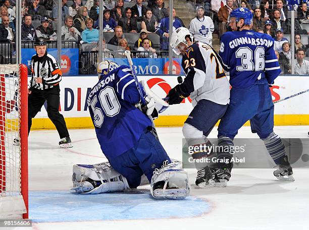 Carl Gunnarsson of the Toronto Maple Leafs battles with Jim Slater of the Atlanta Thrashers in front of goalie Jonas Gustavsson of the Maple Leafs...