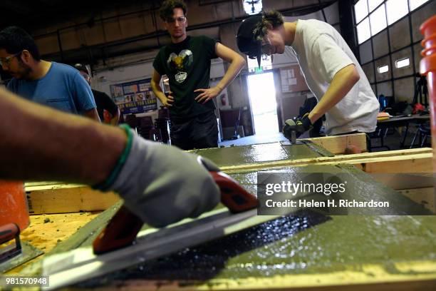 Students Ashton Neil, right, and Ryan Casselberry, middle, learn the finer points of of concrete finishing as they take part in the Construction...