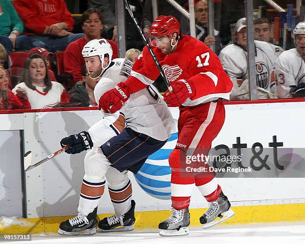 Ryan Whitney of the Edmonton Oilers and Patrick Eaves of the Detroit Red Wings battle to the loose puck during an NHL game at Joe Louis Arena on...