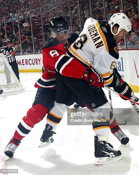 Dennis Wideman of the Boston Bruins and Dainius Zubrus of the New Jersey Devils battle hard in the corner during the game at the Prudential Center on...