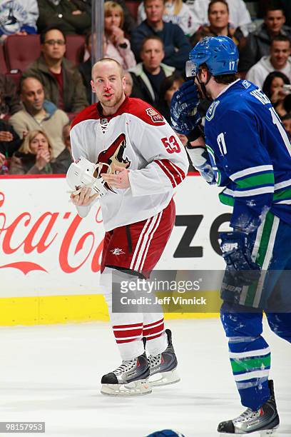 Ryan Kesler of the Vancouver Canucks and Derek Morris of the Phoenix Coyotes exchange a few words as they skate over to the penalty box during their...