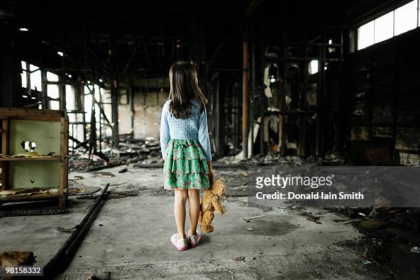 girl with teddy bear in burned building - house rubble stock pictures, royalty-free photos & images