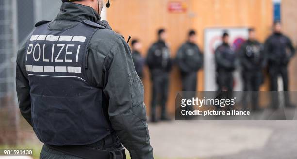 March 2018, Germany, Stuttgart: Police officers standing at the entrance to the court before the start of the trial against alleged leader of the...