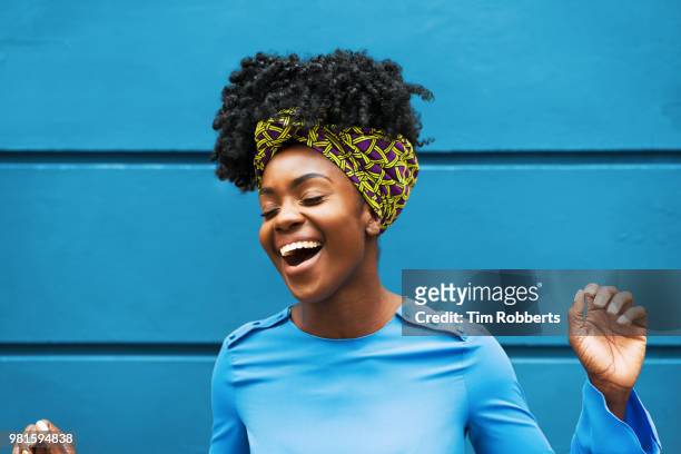 joyous woman infront of wall - afro hairstyle stock-fotos und bilder