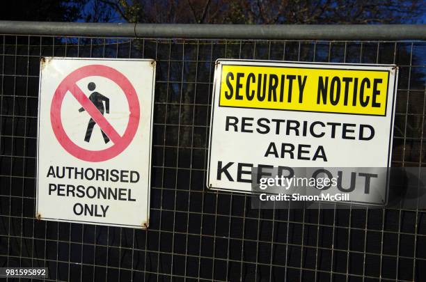 'authorised personnel only' and 'security notice: restricted area. keep out' signs on a wire security fence around a construction site - restricted area sign ストックフォトと画像