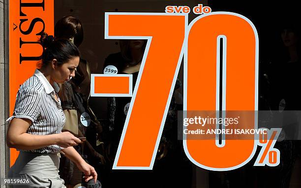 By KATARINA SUBASIC A pedestrian walks past a Belgrade shop displaying price reductions on March 26, 2010. Having lived for decades in a devastated...