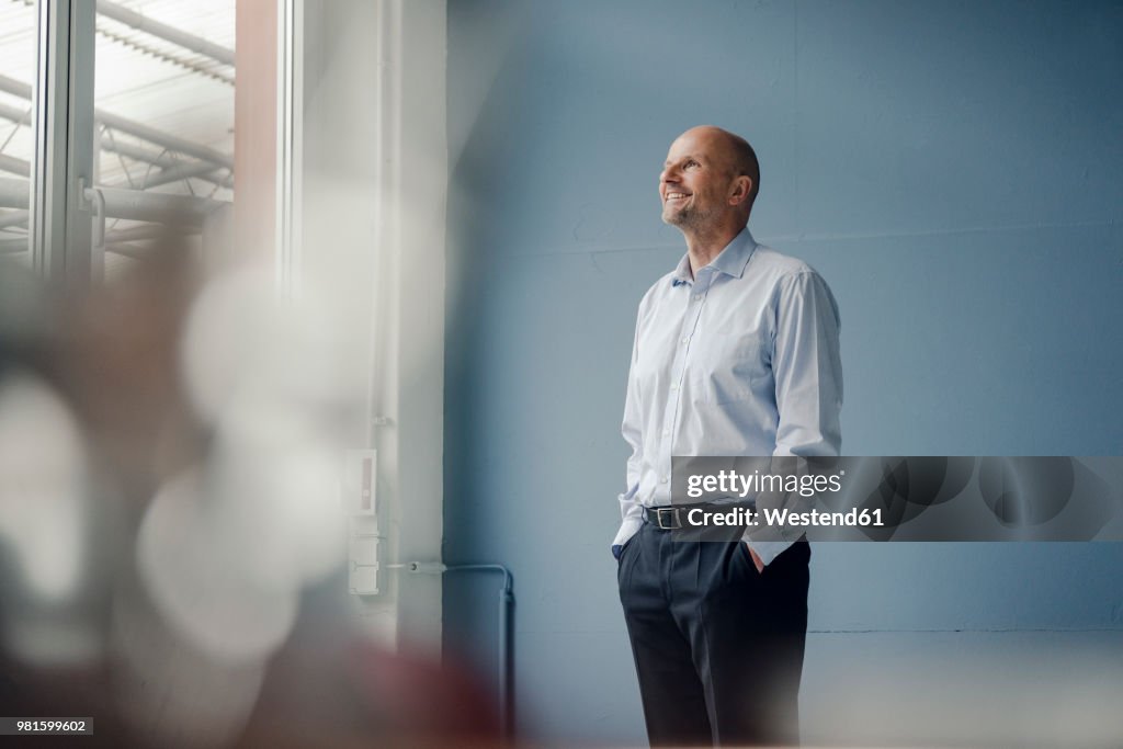 Smiling mature businessman looking out of window