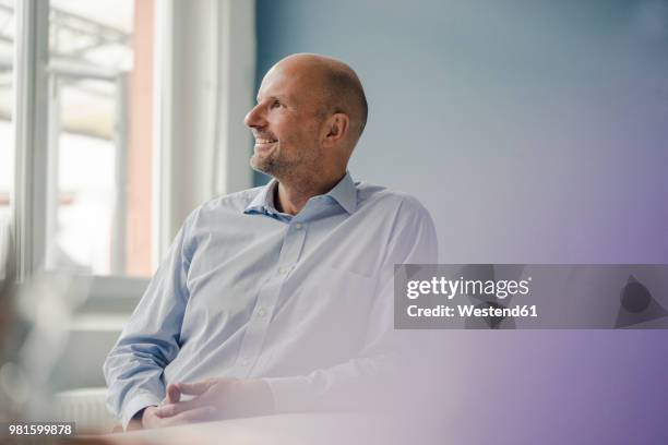 smiling mature businessman looking out of window - selective focus stock pictures, royalty-free photos & images