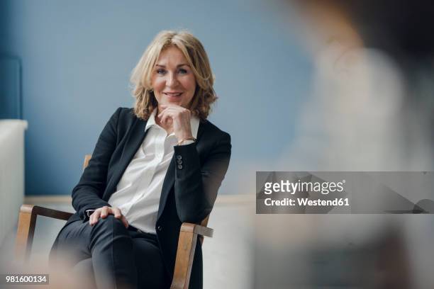portrait of smiling senior businesswoman sitting in chair - selective focus stock-fotos und bilder
