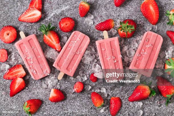 four homemade strawberry ice lollies, ice and strawberries on marble - aardbeienijs stockfoto's en -beelden