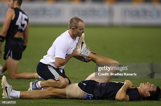 Michael Jamison performs stretching excersies with his team physio during a Carlton Blues AFL training session at The Gabba on March 31, 2010 in...