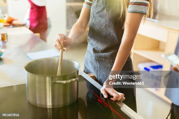 woman stirring in cooking pot in kitchen - keramische plaat stockfoto's en -beelden