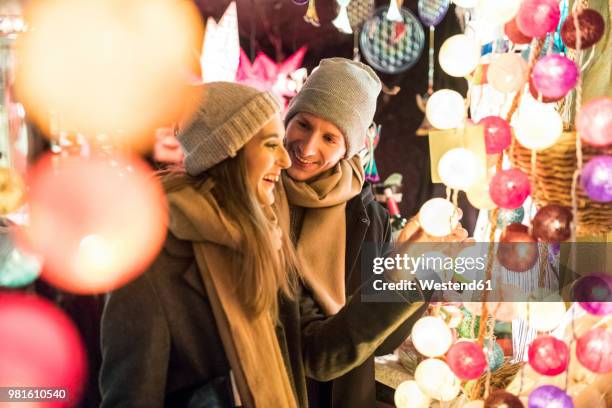 young couple watching offerings at christmas market - christkindlmarkt stock-fotos und bilder