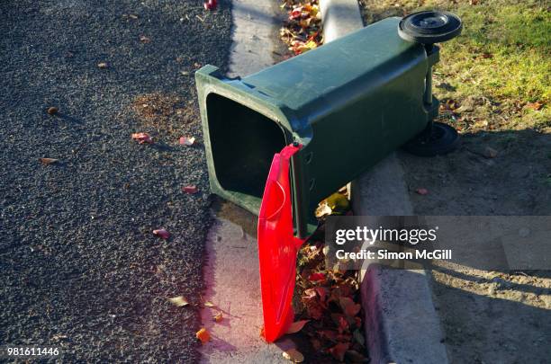 plastic wheeled rubbish bin laying on the road after rubbish collection - wheelie bin stock pictures, royalty-free photos & images