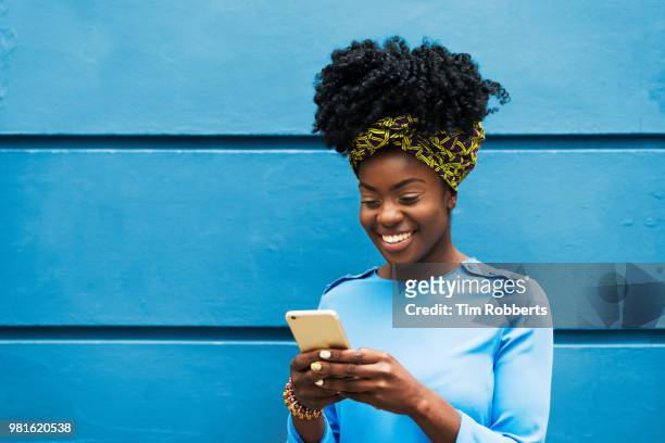 woman smiling with smart phone - african colors stock pictures, royalty-free photos & images