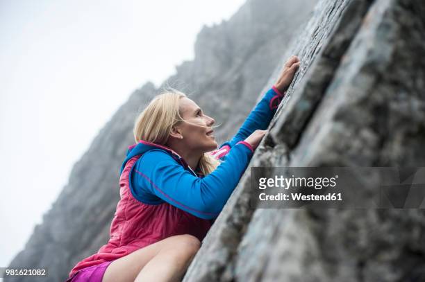 austria, salzburg state, filzmoos, female hiker climbing on rock - rock climbing stock-fotos und bilder