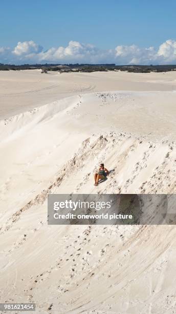 Australia. Western Australia. Lancelin. A woman slides down the sand dunes.