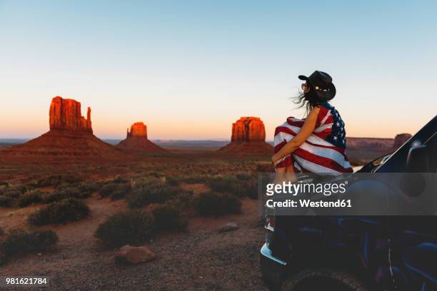 usa, utah, woman with united states of america flag enjoying the sunset in monument valley - hood clothing stock pictures, royalty-free photos & images