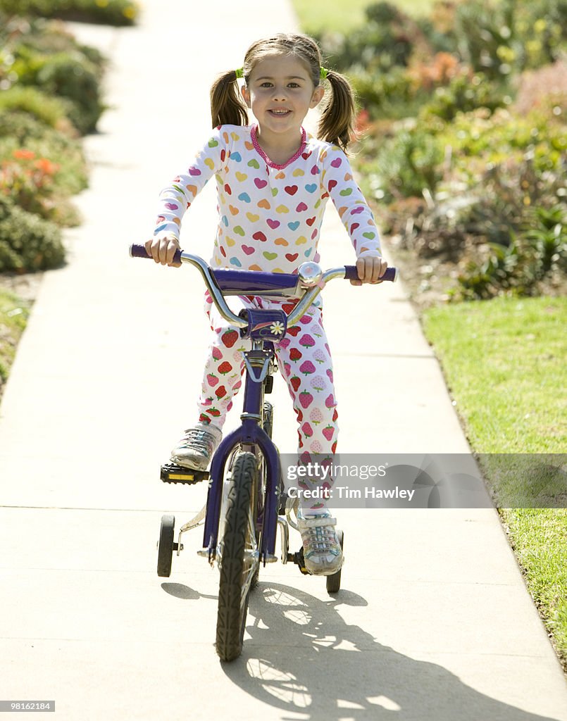 Girl in pigtails on bike w/ training wheels