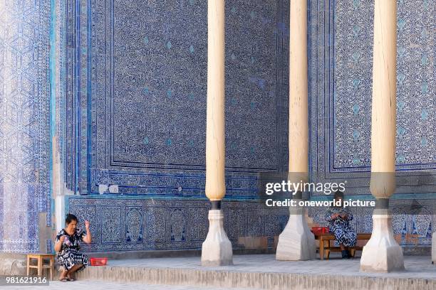 Uzbekistan. Women sit in the shadow of an old madrasah and knit.