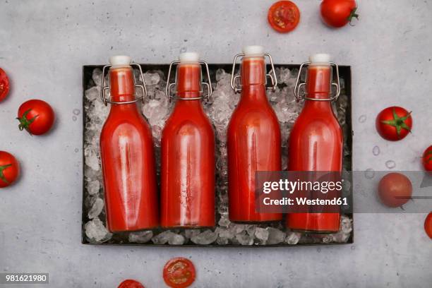 row of four ice-cooled swing top bottles with homemade tomato juice - tomato juice stock pictures, royalty-free photos & images